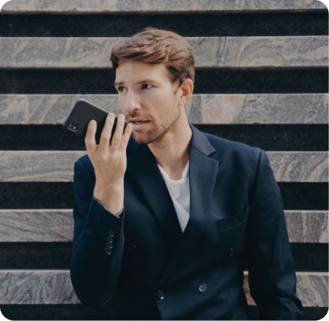 Man in a suit using speech to text app on his mobile while on the go