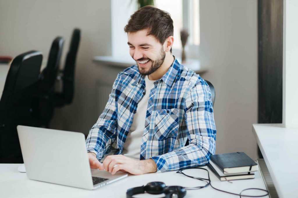 Glücklicher Mann bei der Arbeit am Laptop