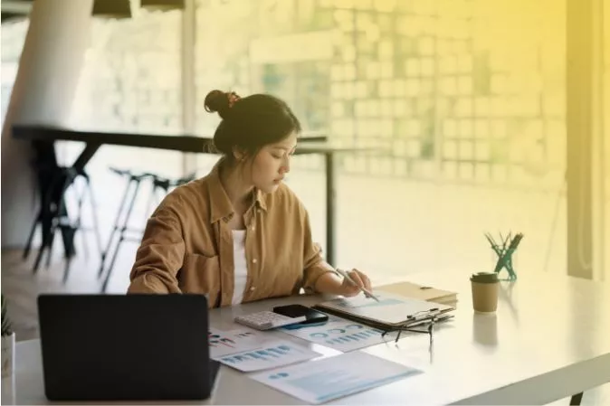 Woman studying multiple datasheets on paper at a desk