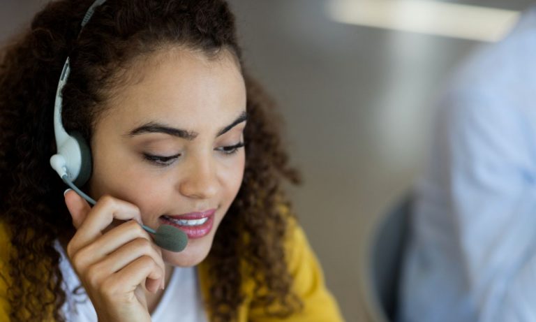 Customer Service Girl in Yellow Sweater with Curly Hair wearing and talking through a Headset