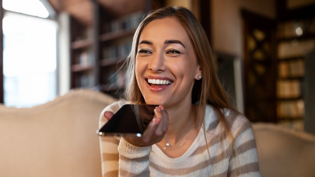 Young woman using voice translator to transcribe speech at home