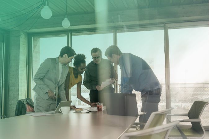 4 people participating in a group meeting in an office with big windows