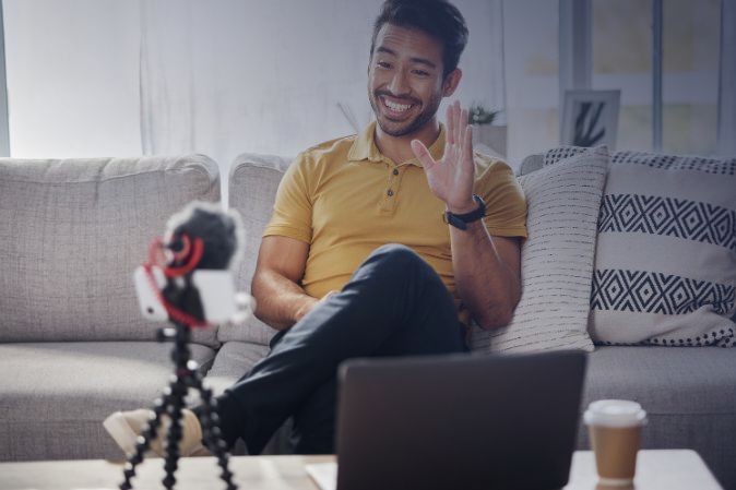 Man waving at webcam at home sitting on his couch