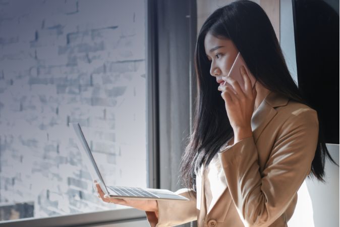 Woman looking at her laptop and being on the phone at the same time