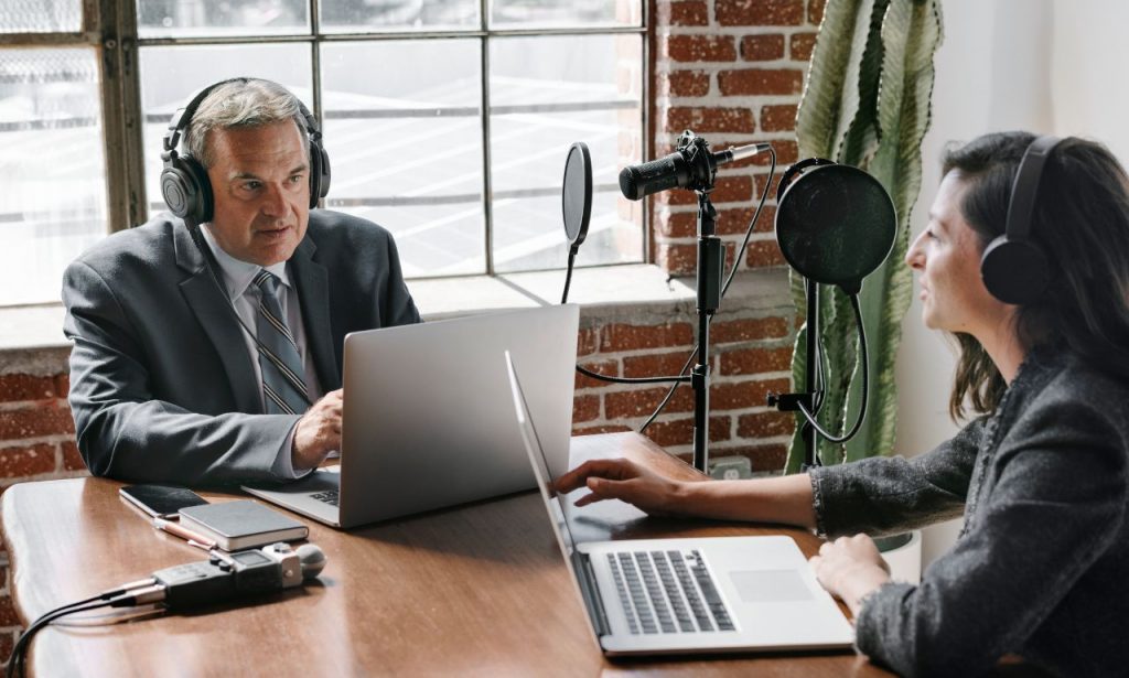 Older man interviewing woman on a podcast and transcribing his material afterwards