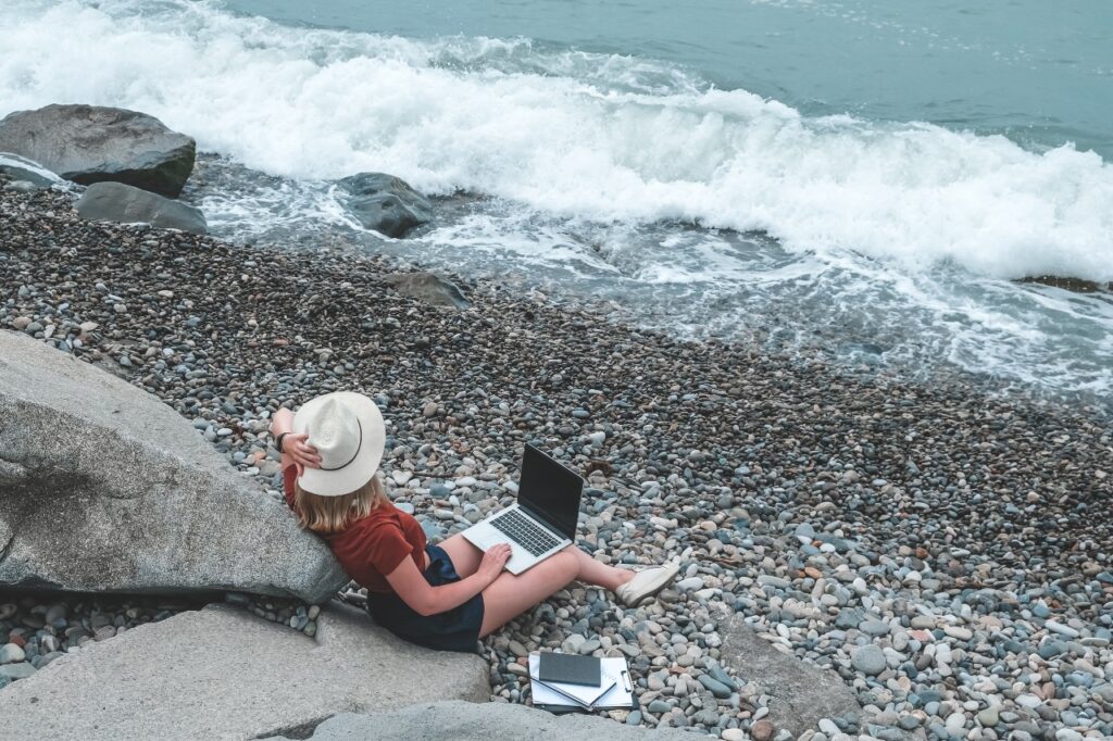 Blonde woman working remotely on the beach
