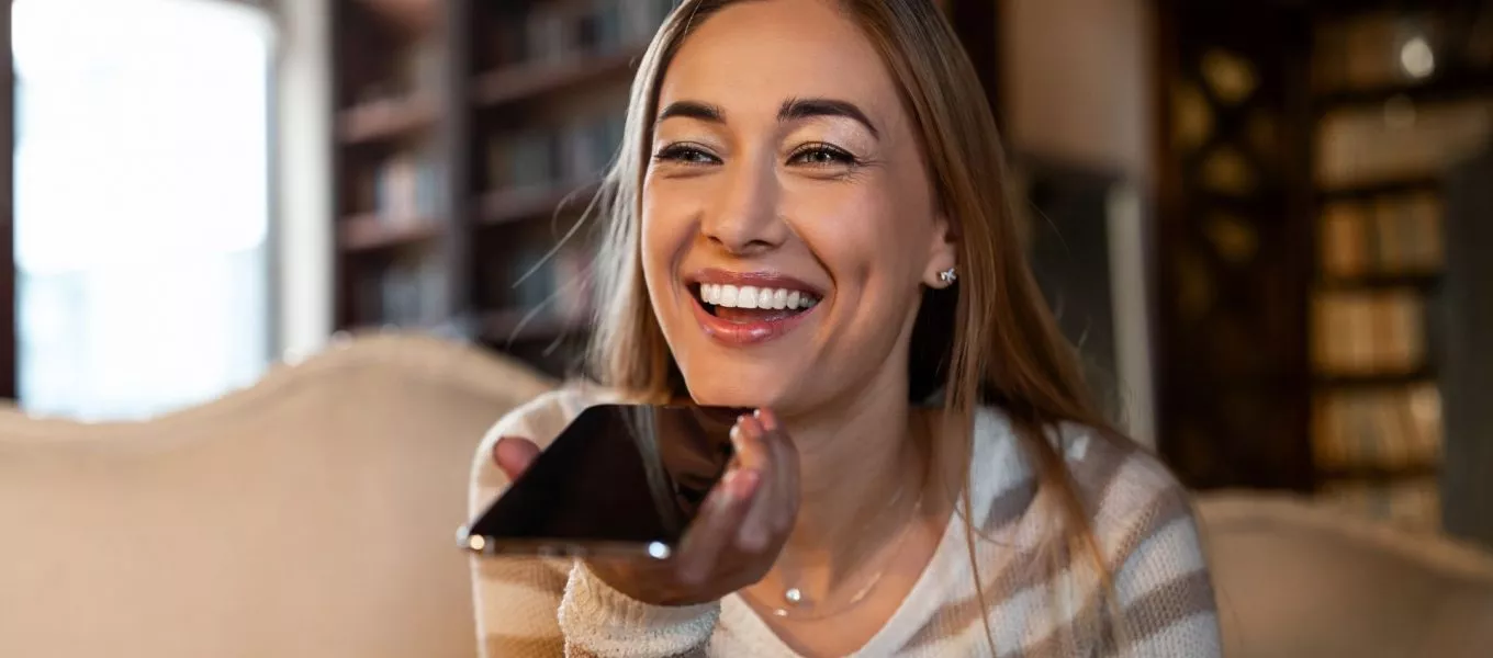 Young woman using voice translator to transcribe speech at home