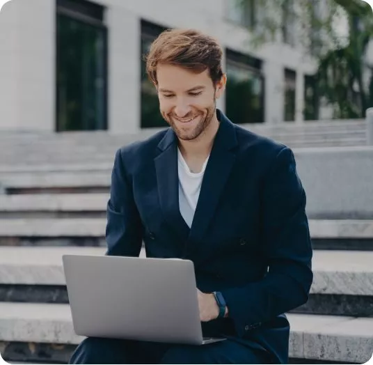 Egy férfi speech to text alkalmazást használ a laptopján a lépcsőn ülve