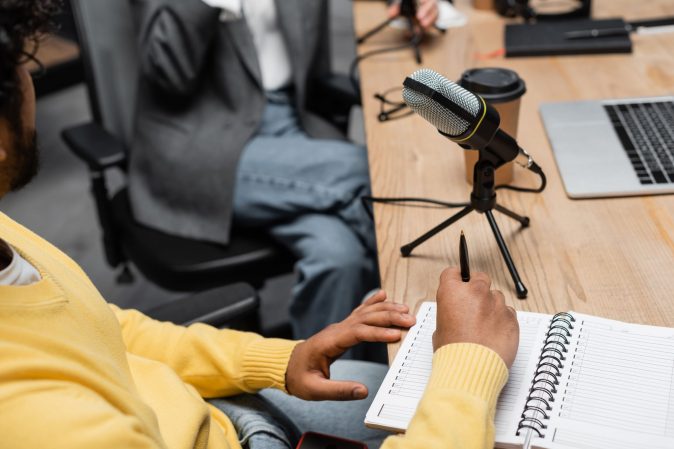 cropped-view-of-indian-broadcaster-holding-noteboo-2023-11-27-04-59-01-utc (1) Woman dictating and recording meeting in order to transcribe it